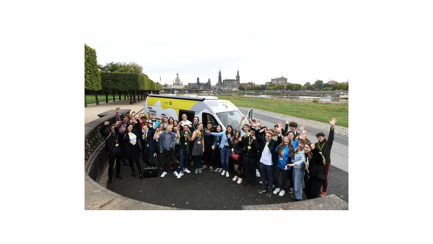Members of the Dresden 2025 Youth Council wave at the camera on the banks of the Elbe river in Dresden.