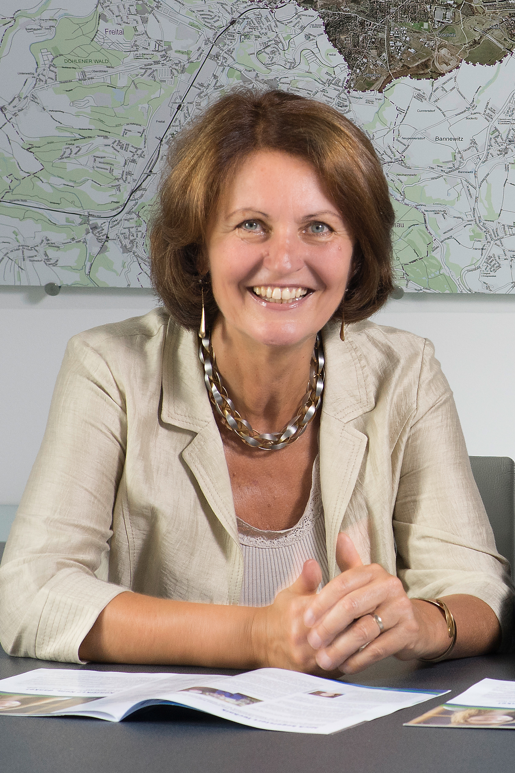 Portraitfoto von Gunda Röstel, Kaufmännische Geschäftsführerin der Stadtentwässerung Dresden, am Tisch sitzend vor einem Stadtplan