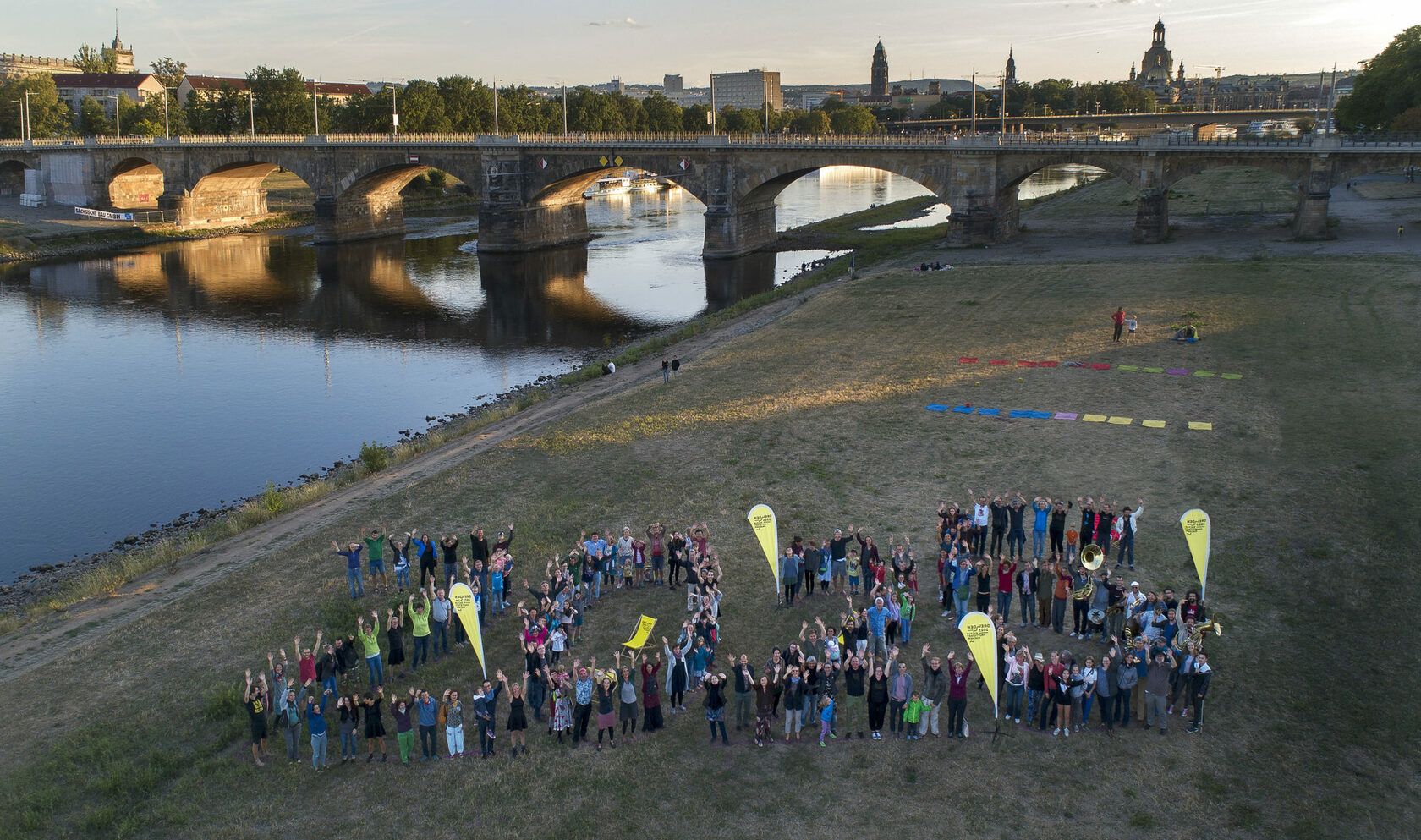 Gruppenfoto von zahlreichen Bürgerinnen und Bürgern, die auf den Dresdner Elbwiesen die Zahl 2025 formen und winken.