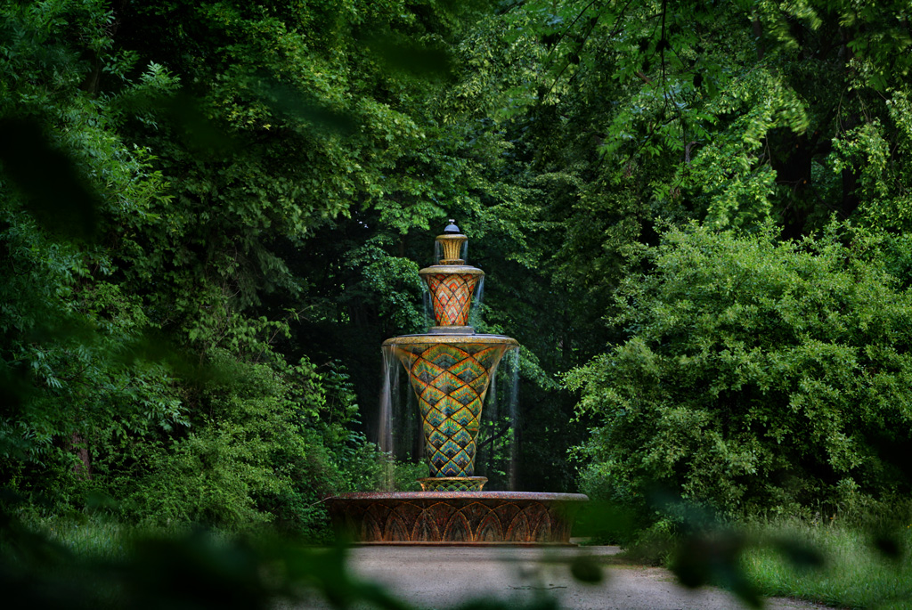 Blick auf den Mosaikbrunnen im Großen Garten, umrahmt von grünen Bäumen