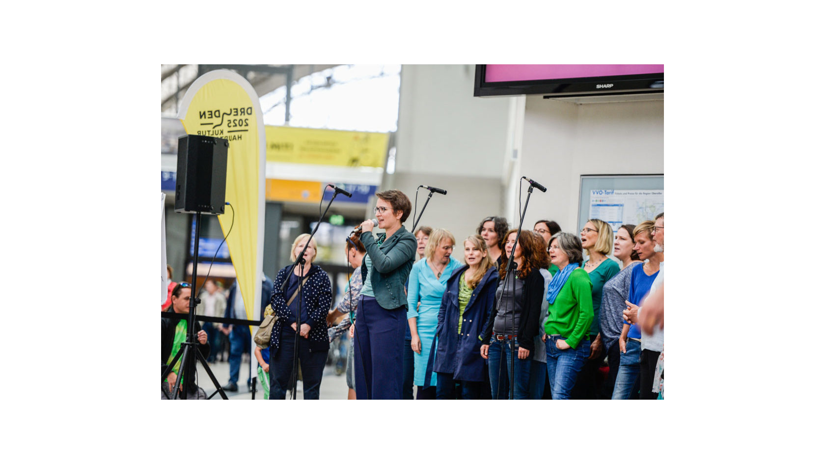 Der Dresdner Chor „Blau- & Grüntöne“ singt in der Kuppelhalle des Dresdner Hauptbahnhofs, arrangiert von der Chorleiterin.