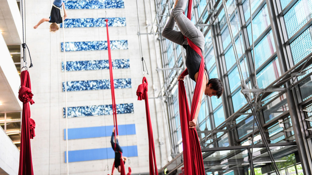 Several people float in a red cloth suspended from the ceiling above the floor at the Max Planck Institute of Molecular Cell Biology.