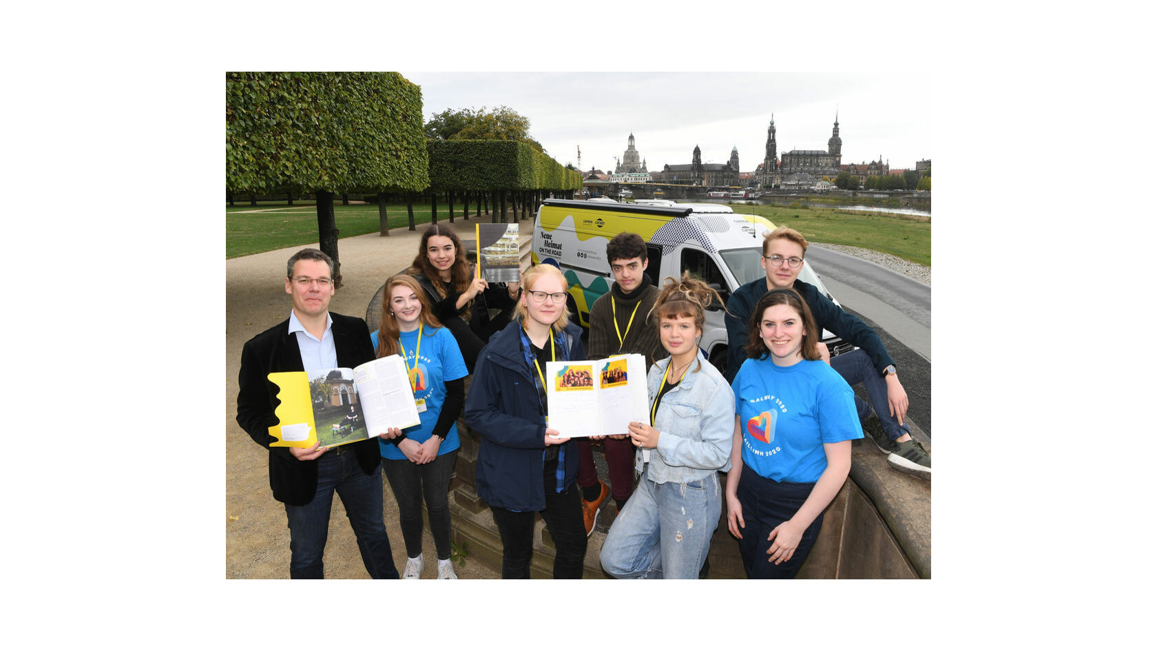 Dr. David Klein, head of the Bid Office Dresden 2025, presents the bid book on the banks of the Elbe river in Dresden together with members of the Dresden 2025 Youth Council.