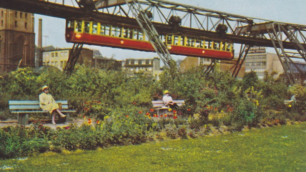 Historisches Foto der Wuppertaler Schwebebahn, im Vordergrund sitzen zwei Damen auf einer Bank.