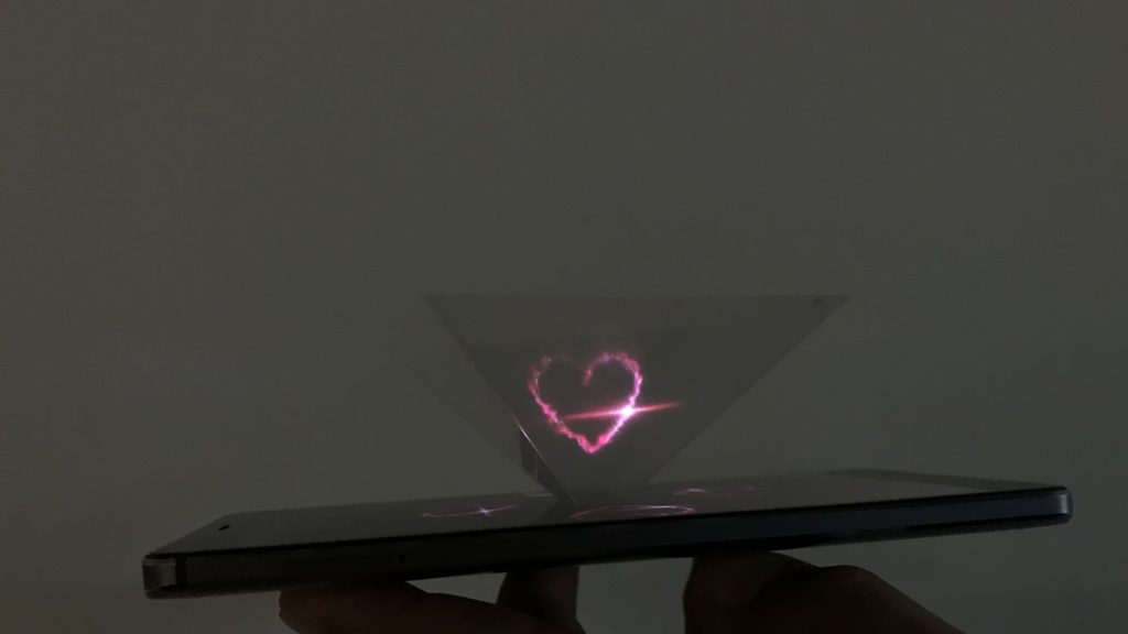 View of a smartphone, a heart appears above it in a triangle.