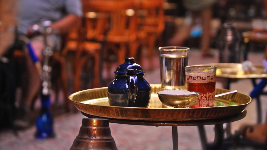 View of a golden tray with a blue pot, tea glasses and a sugar bowl.