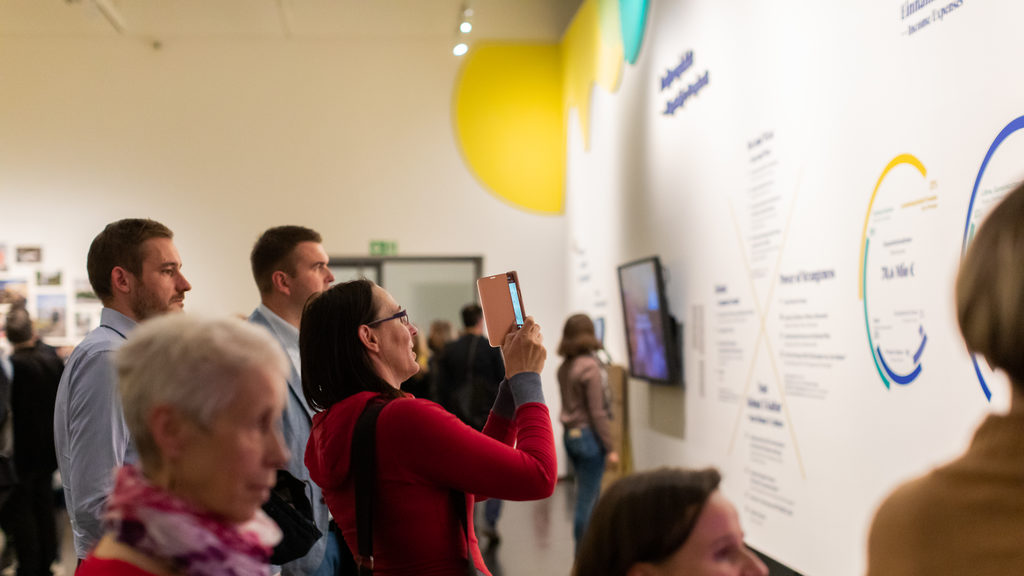 Several people look at an exhibition wall in the Dresden 2025 showroom at the Deutsches Hygiene-Museum Dresden.